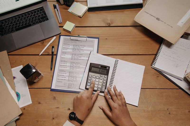 An accountant working on a calculator beside a clipboard