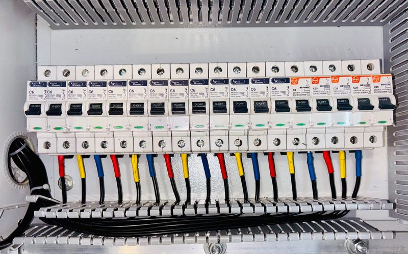 A row of circuit breakers with colour-coded wiring