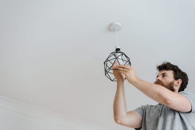 A man fitting a pendant light to a ceiling rose
