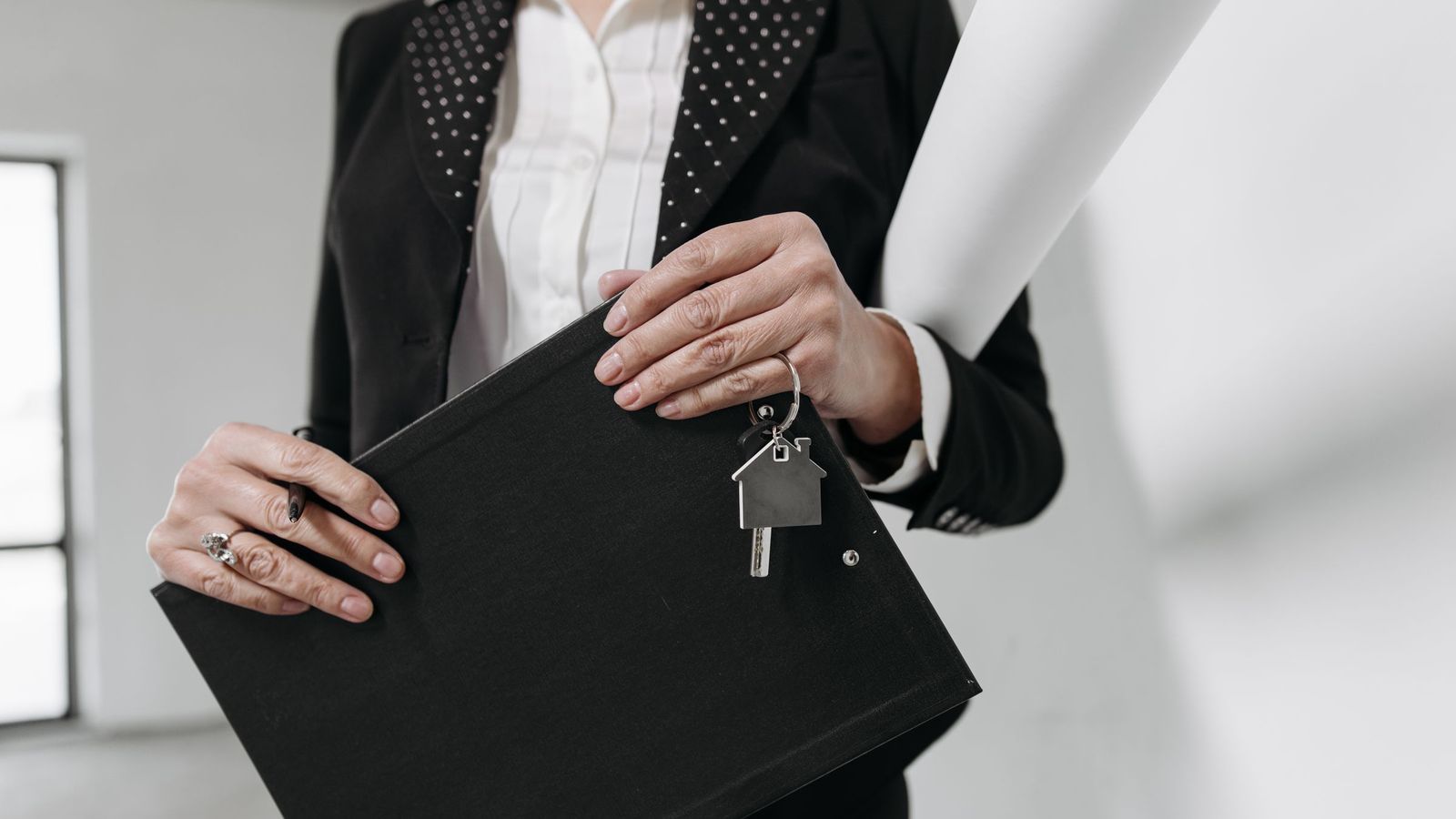 An estate agent holds a set of keys and a clipboard in an office.