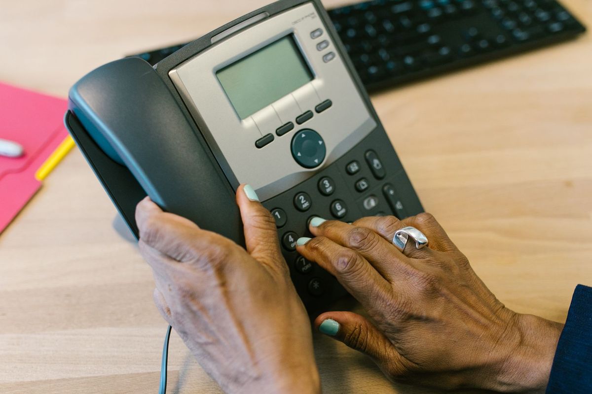 Hands dialling on an office desk phone