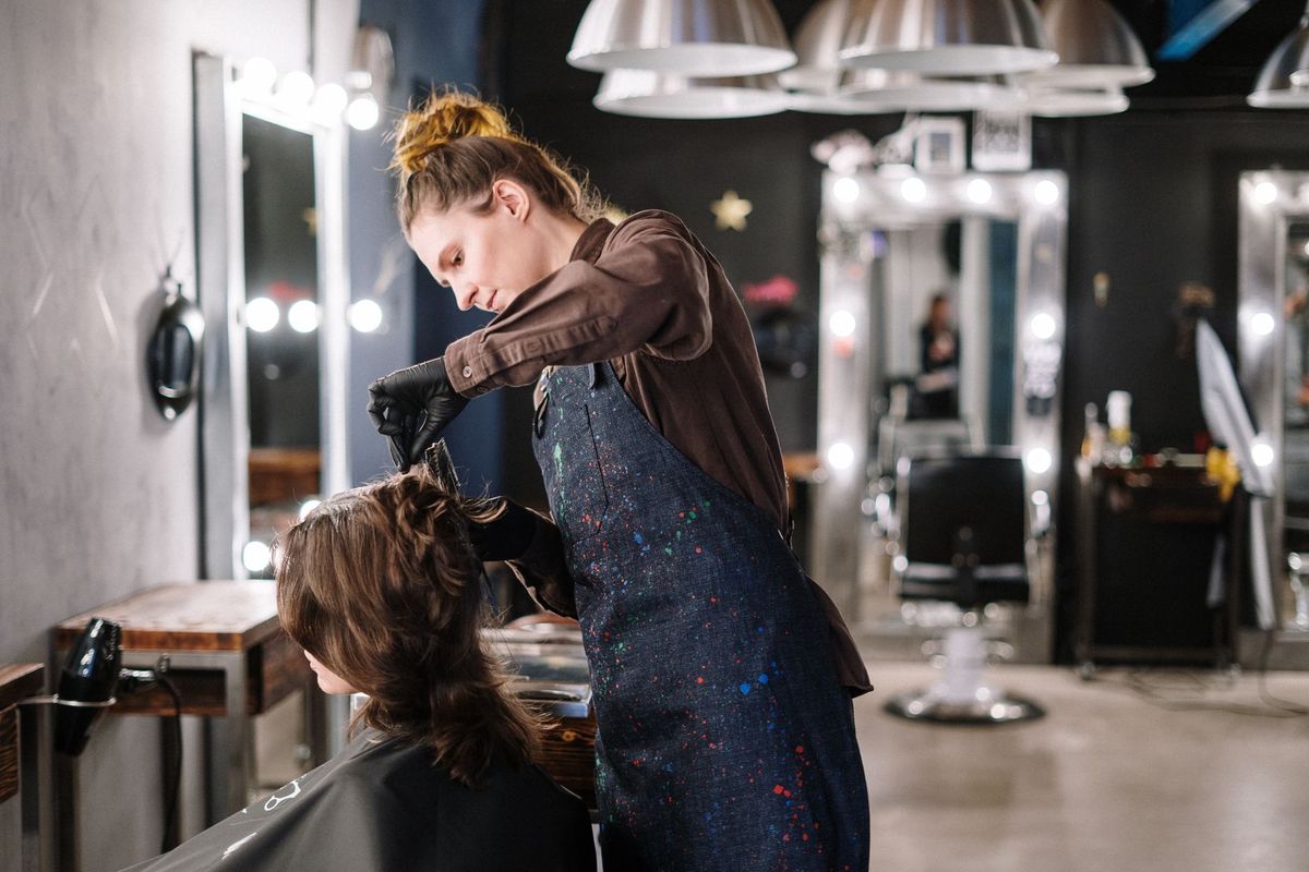 A hairdresser with her hands full, styling a client's hair