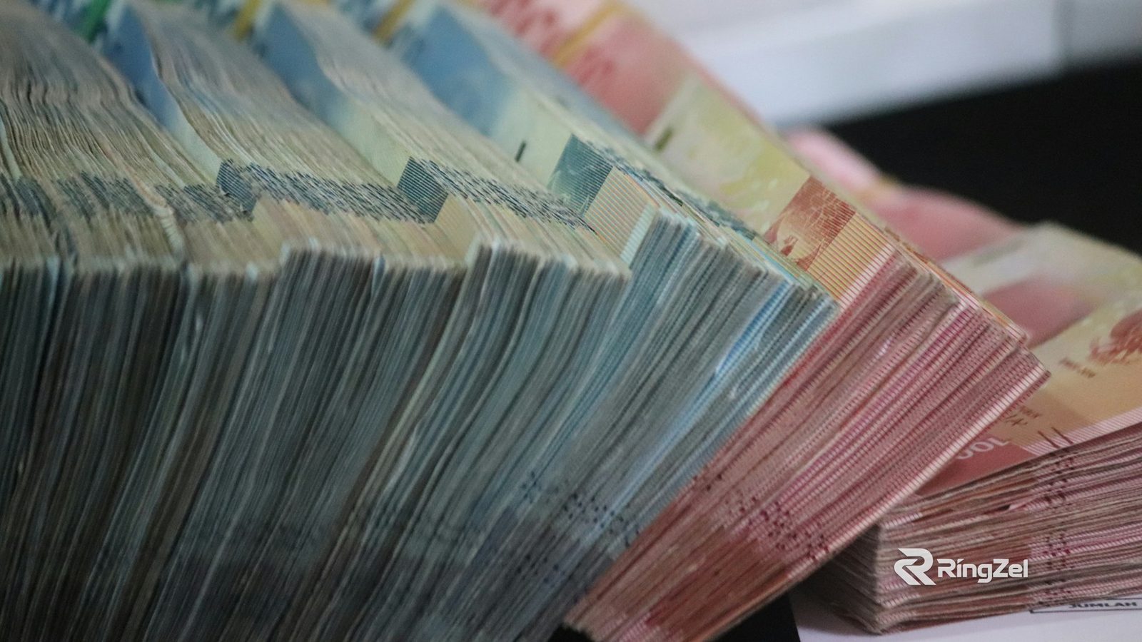 Thick stacks of banknotes fanned out on a table.