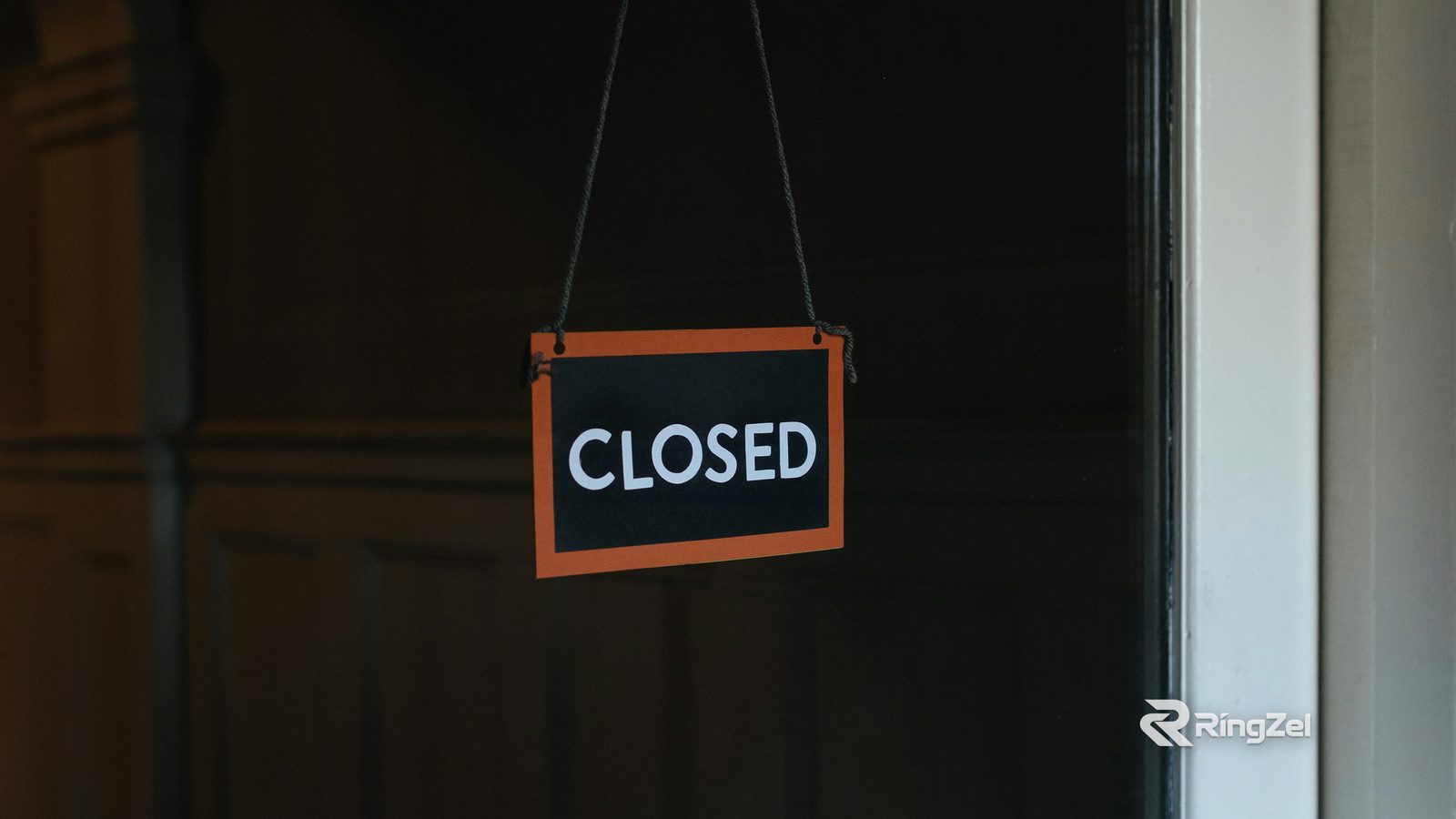 A Closed sign hanging inside the glass of a shop door.