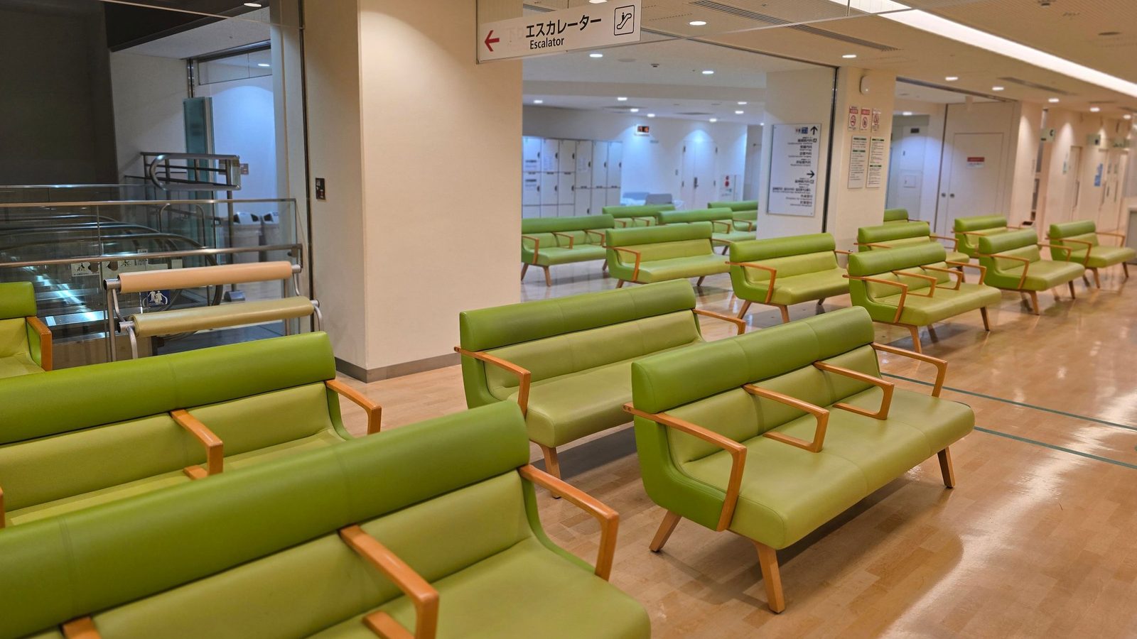 An empty hospital waiting area with rows of green seats.