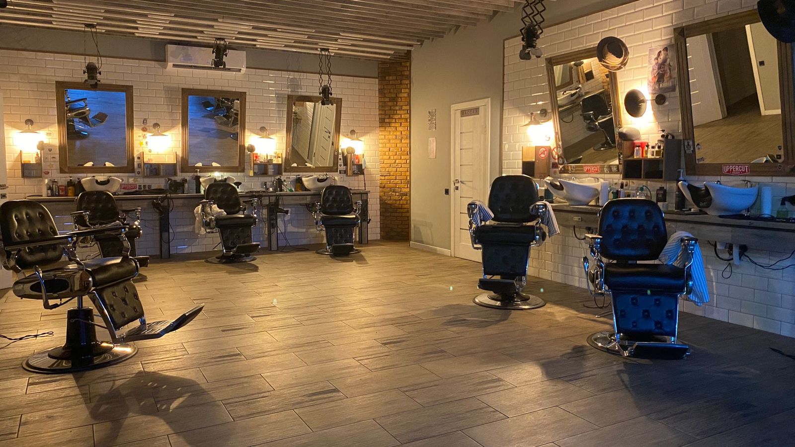 Empty styling chairs and mirrors in a quiet salon with a tiled floor.