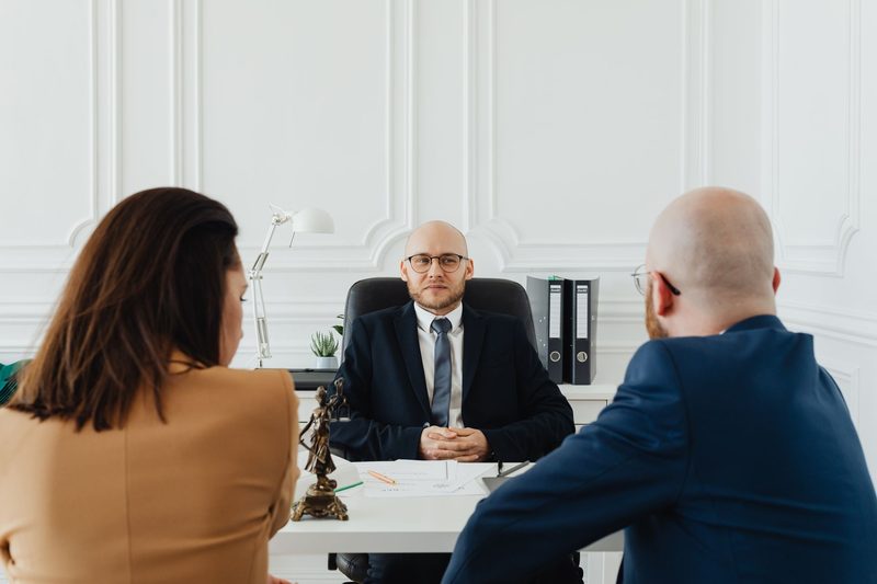A solicitor meeting two clients at a desk