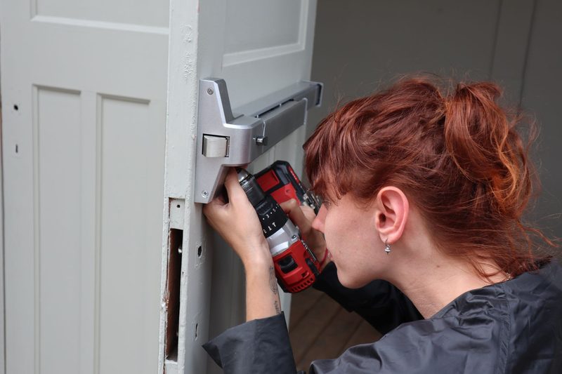 A locksmith drilling to fit a lock to a door