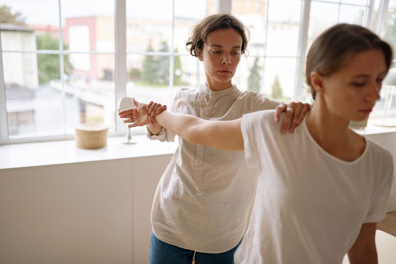 A physiotherapist guiding a patient's outstretched arm by a window