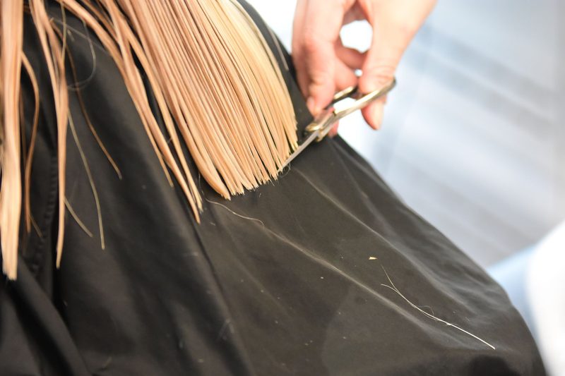 A stylist cutting a client's blonde hair